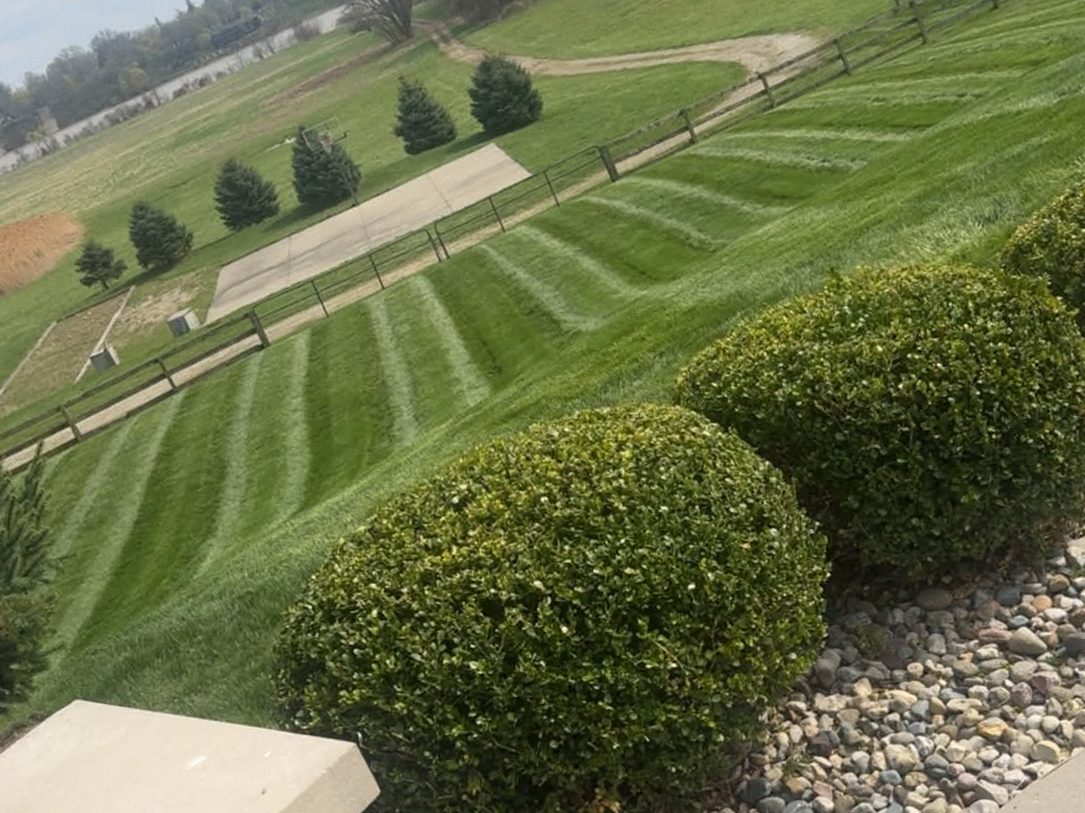 Estate lawn mowed in clean stripes sweeping down toward a pond