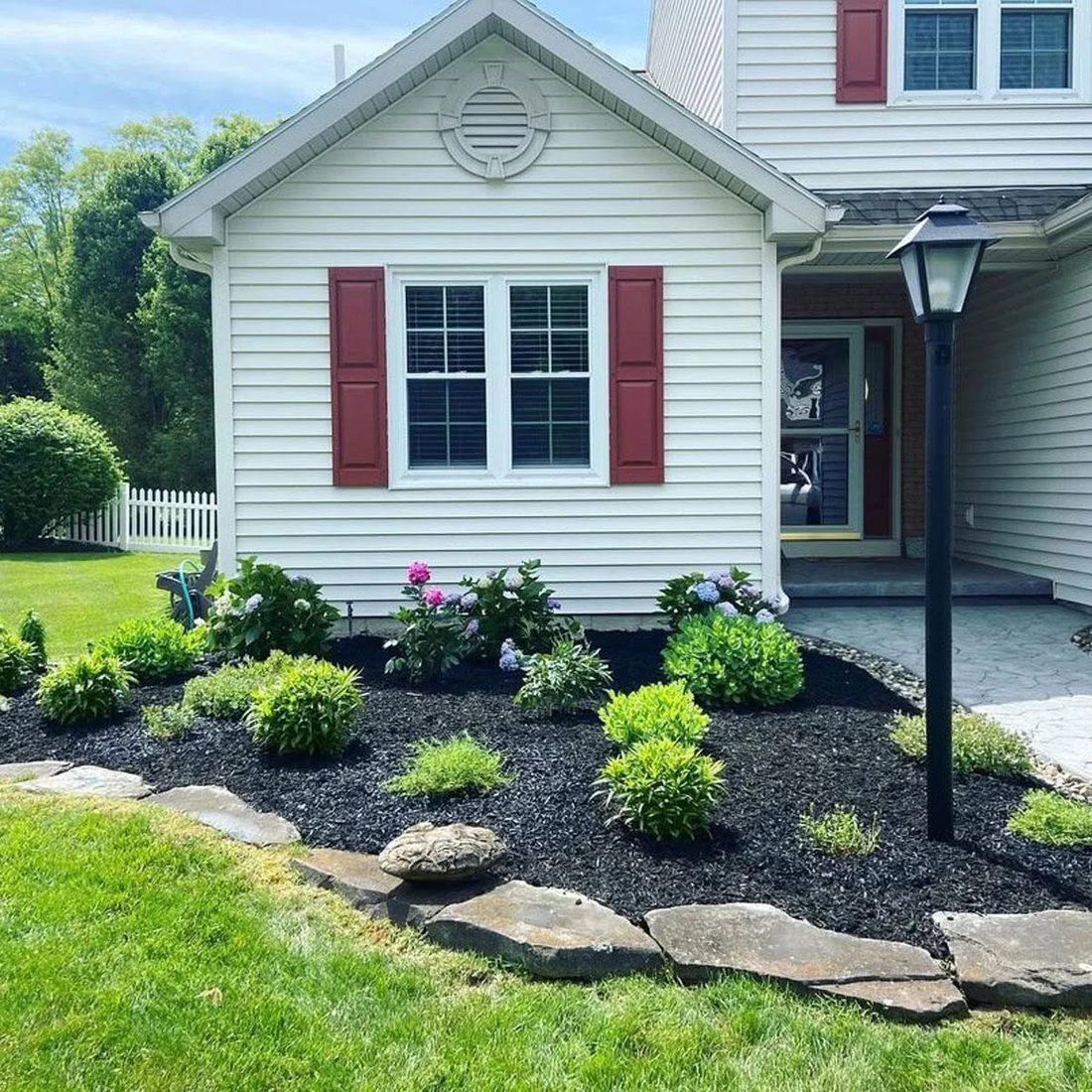 Fresh black-mulch beds and trimmed shrubs along a home's front