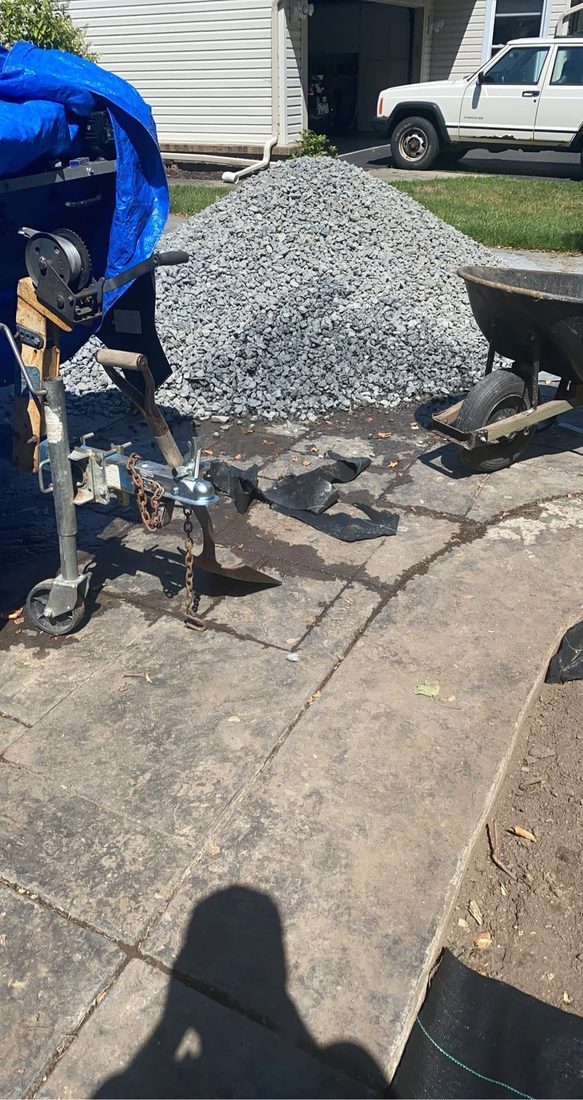 Gravel and materials staged on a driveway for a hardscape job