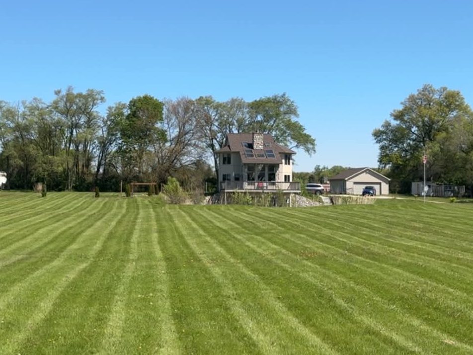 Wide open lawn cut in crisp stripes under a clear blue sky